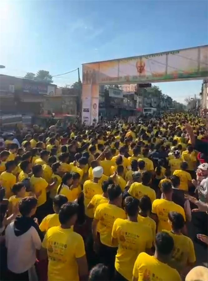 Thousands of runners in yellow marathon shirts filling the road at the Mahilpur start line